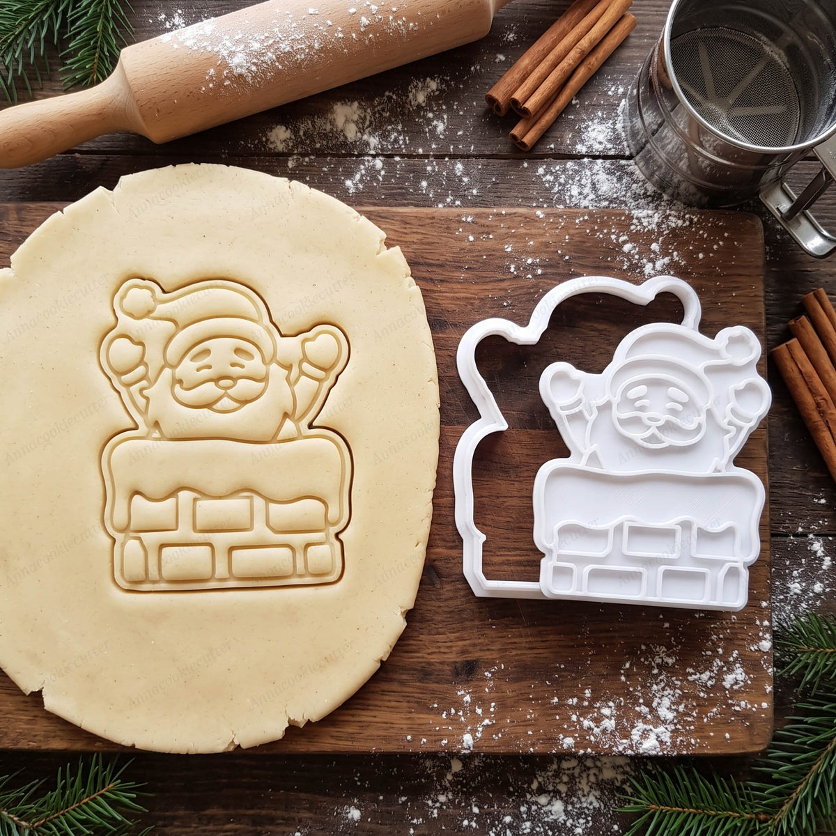 Tagliabiscotti e timbro bianchi di Babbo Natale nel camino, accanto alla loro impronta nella pasta frolla.
