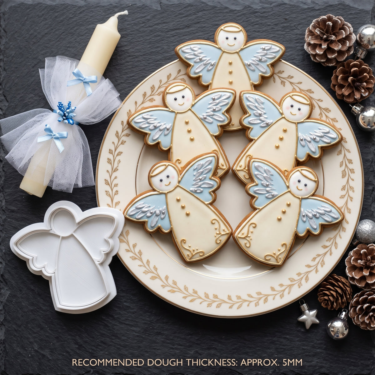 Biscotti a forma di angelo decorati in bianco e azzurro su un piatto, con formina bianca accanto.