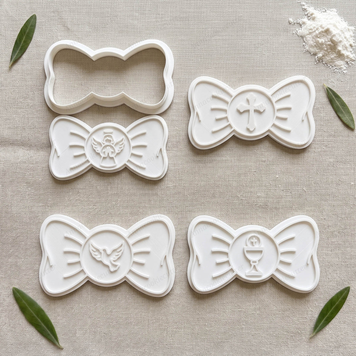  Set con un tagliabiscotti a fiocco e quattro timbri bianchi con angelo, croce, colomba e calice per battesimo e comunione.
