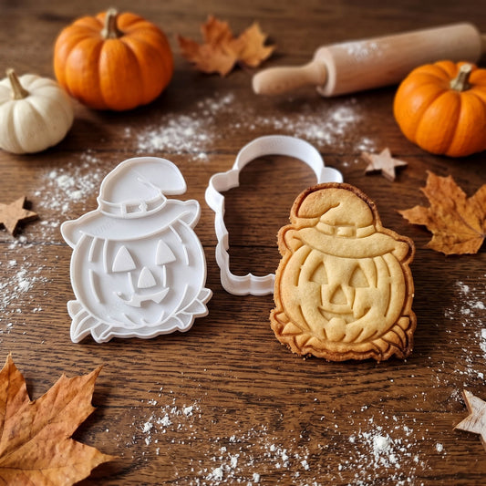 Tagliabiscotti e timbro zucca con cappello da strega accanto a un biscotto Halloween