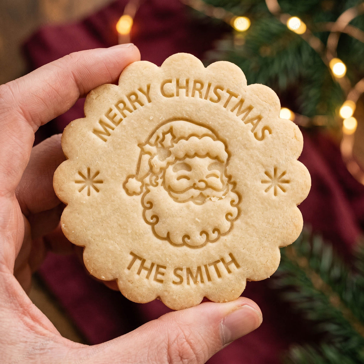 Biscotto dal bordo festonato con Babbo Natale e scritte Merry Christmas e The Smith, davanti alle luci dell’albero di Natale.

